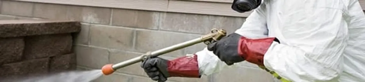 Pest control technician applying exterior insect treatment along a home foundation in Myrtle Beach, SC