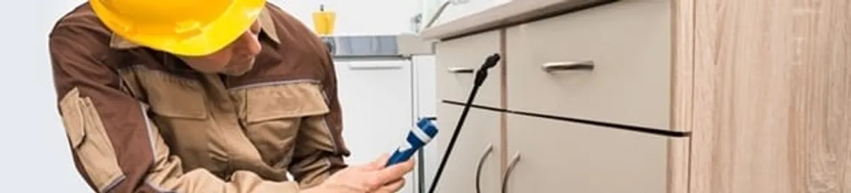 Roach exterminator applying treatment under kitchen cabinets in Myrtle Beach, SC