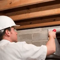 Termite inspection technician checking a basement wall and framing for termite activity in Myrtle Beach, SC